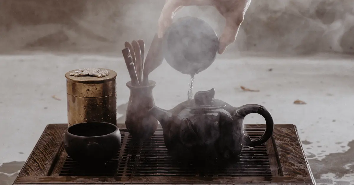 a person pouring hot water into teaware